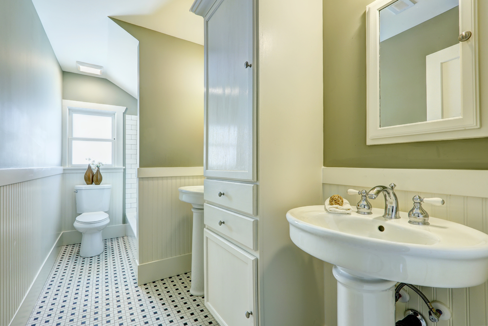 White bathroom interior with siding wall trim, two washbasin stands and cabinet