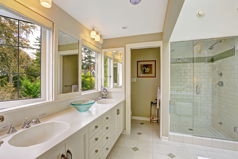 Spacious bright bathroom with white storage combination and glass door shower