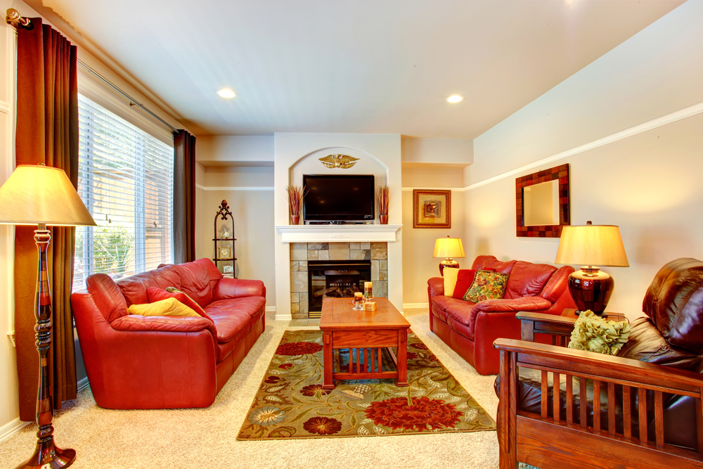 Living room with fireplace, red leather couches and TV in luxury house