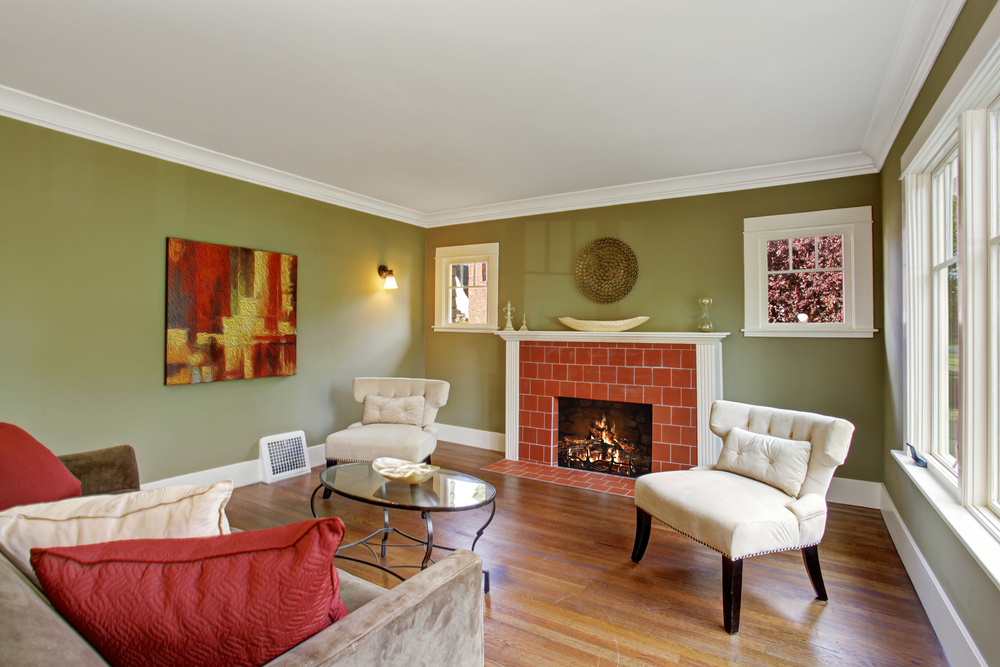 Olive tone family room with fireplace, two white chairs, sofa and glass top coffee table